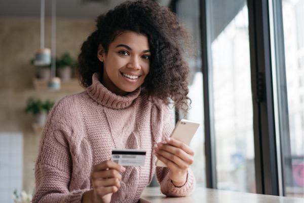 Woman with credit card in one hand and phone in the other.